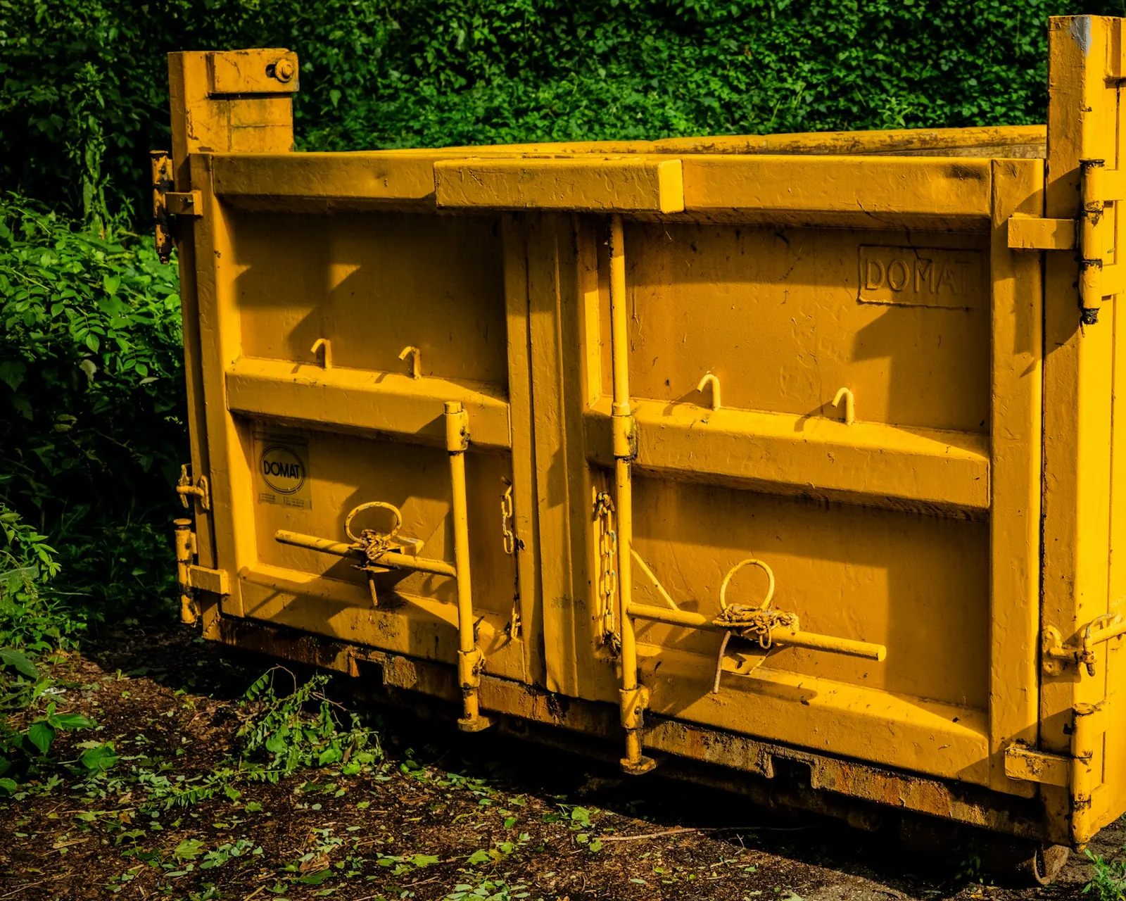 A yellow roll-off dumpster on a brick driveway