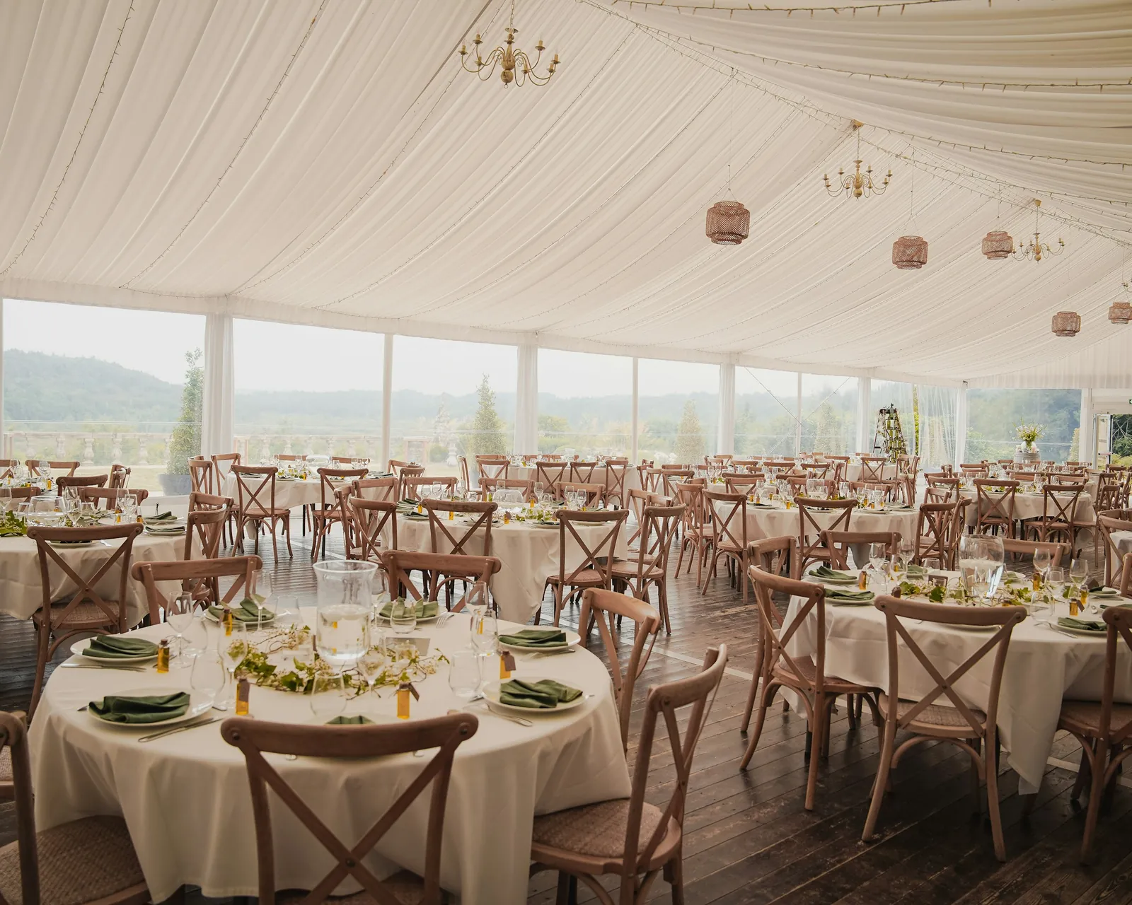 Tables and chairs set for a reception inside a large event tent